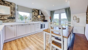 Una cocina moderna con detalles de piedra, un comedor con banco y vistas a través de amplios ventanales.