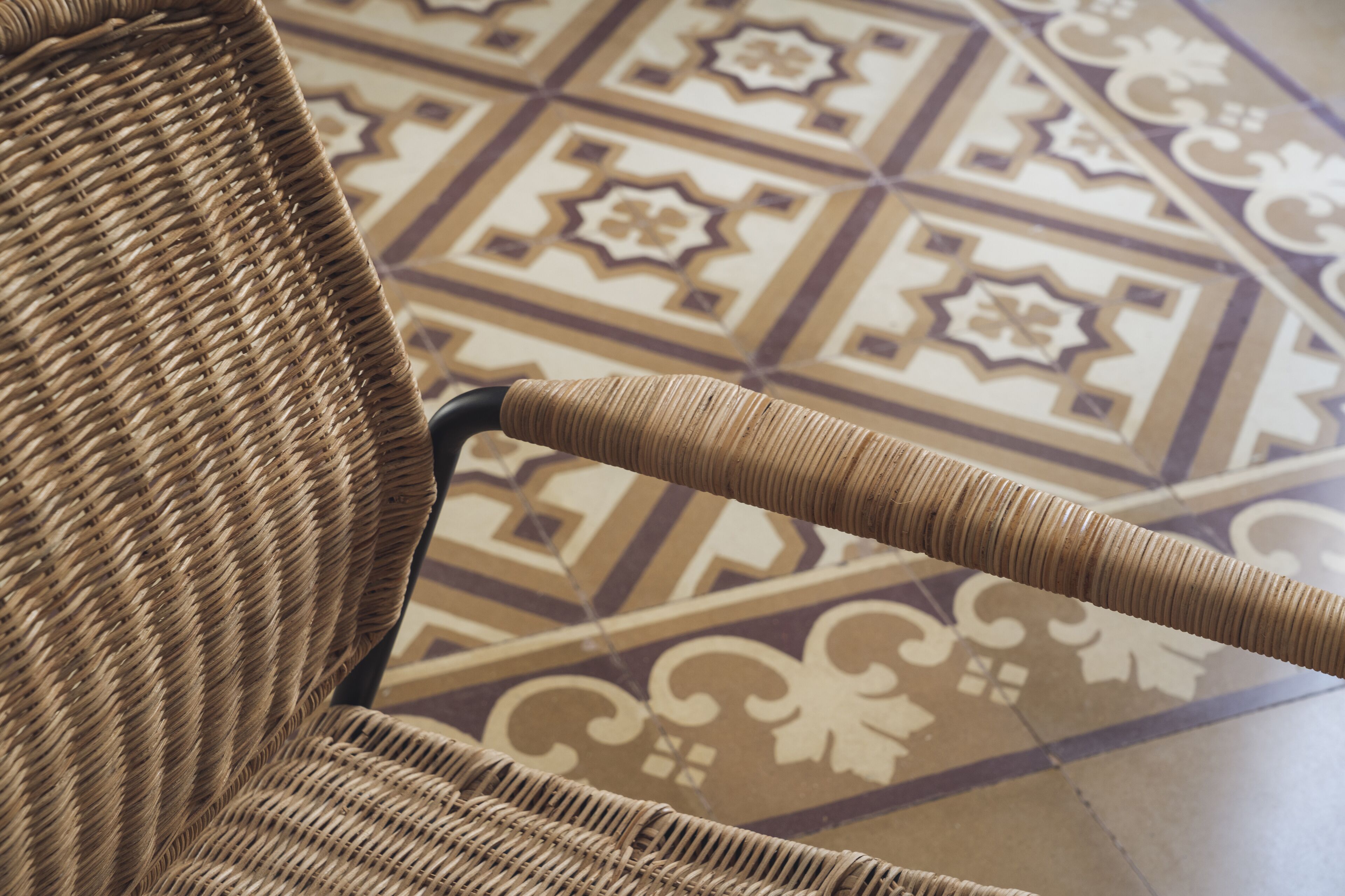 A wicker chair with a textured backrest and a patterned floor.