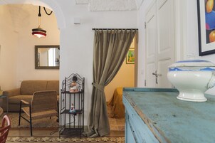 A room with a sofa, a chair, a small table with a figurine, a blue cabinet, and a door with a curtain.