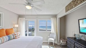 Une chambre à coucher comprenant un lit, un ventilateur de plafond, une télévision, une chaise et une commode.