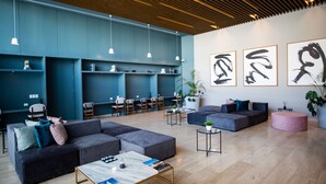 A modern lounge area with sofas, tables, and artwork on the walls. - New Deluxe Unit, Signature Condominium by The Harbor (Mérida)