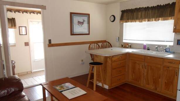 A compact kitchen with wooden cabinets, a dining table, and a bar stool.