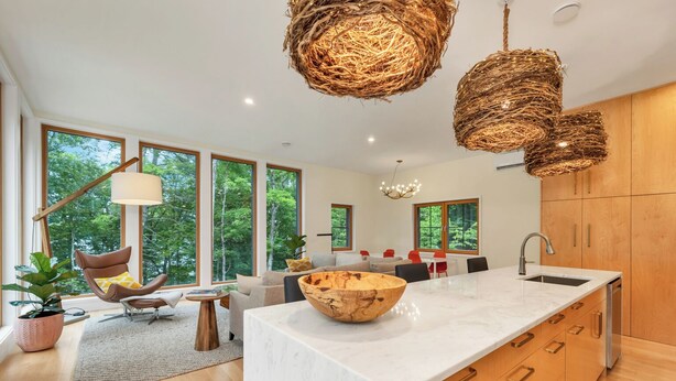 Een moderne keuken met een groot schiereiland, houten kasten en uitzicht op het buiten.