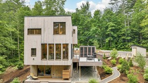 Een modern huis met twee verdiepingen, grote ramen, een terras en een tuin.