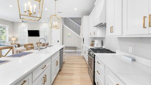 Une cuisine moderne avec des meubles blancs, un îlot central et une cuisinière.