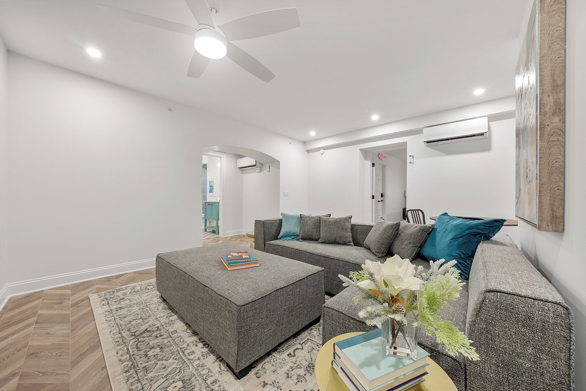 A modern living room with a sectional sofa, a coffee table, and a ceiling fan.