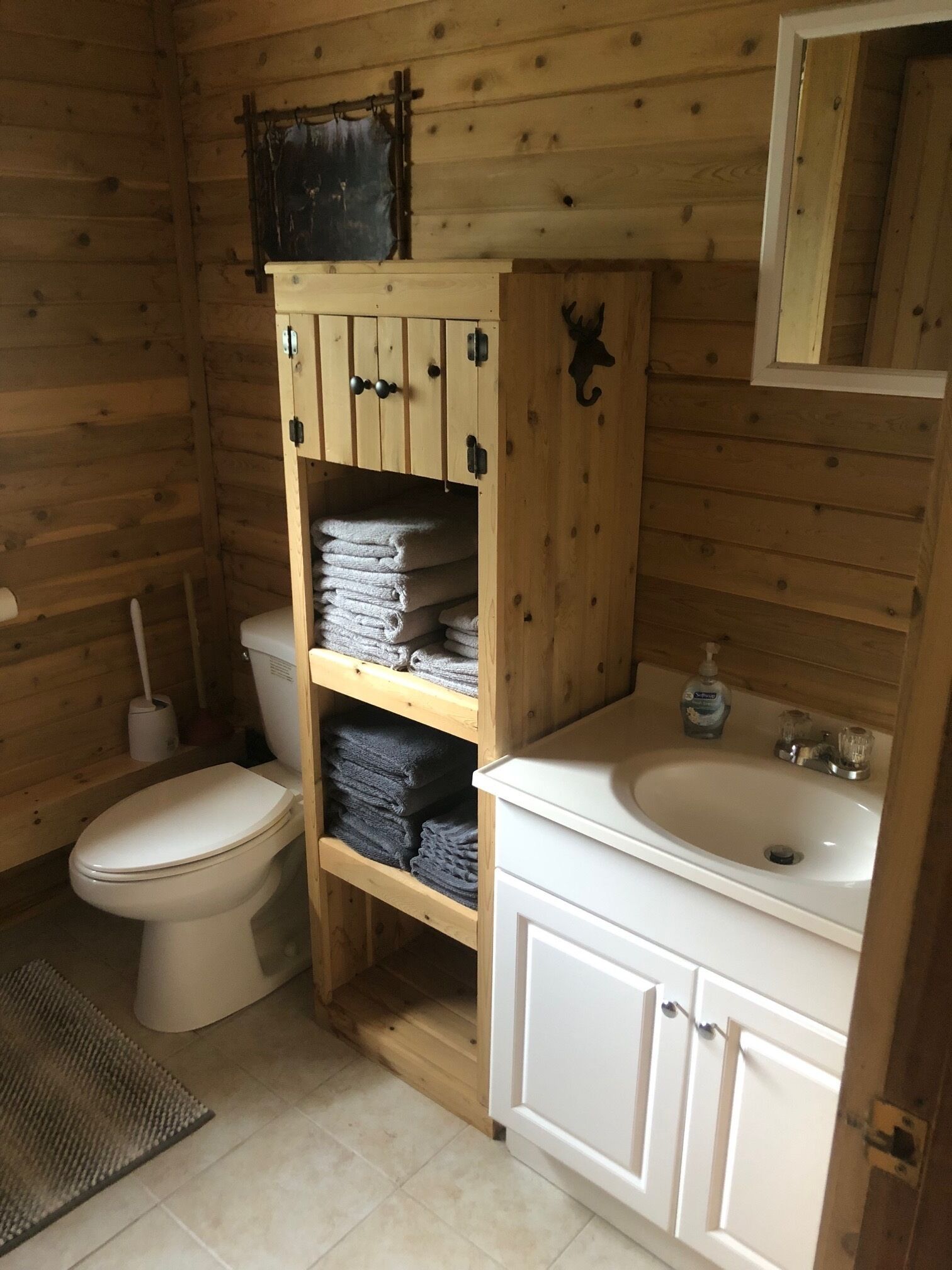 Un baño pequeño de madera con un inodoro, un lavabo y un estante con toallas dobladas.