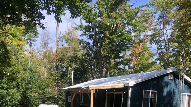 Un chalet rustique doté d ’un porche abrité, d’un foyer extérieur et de meubles de jardin.