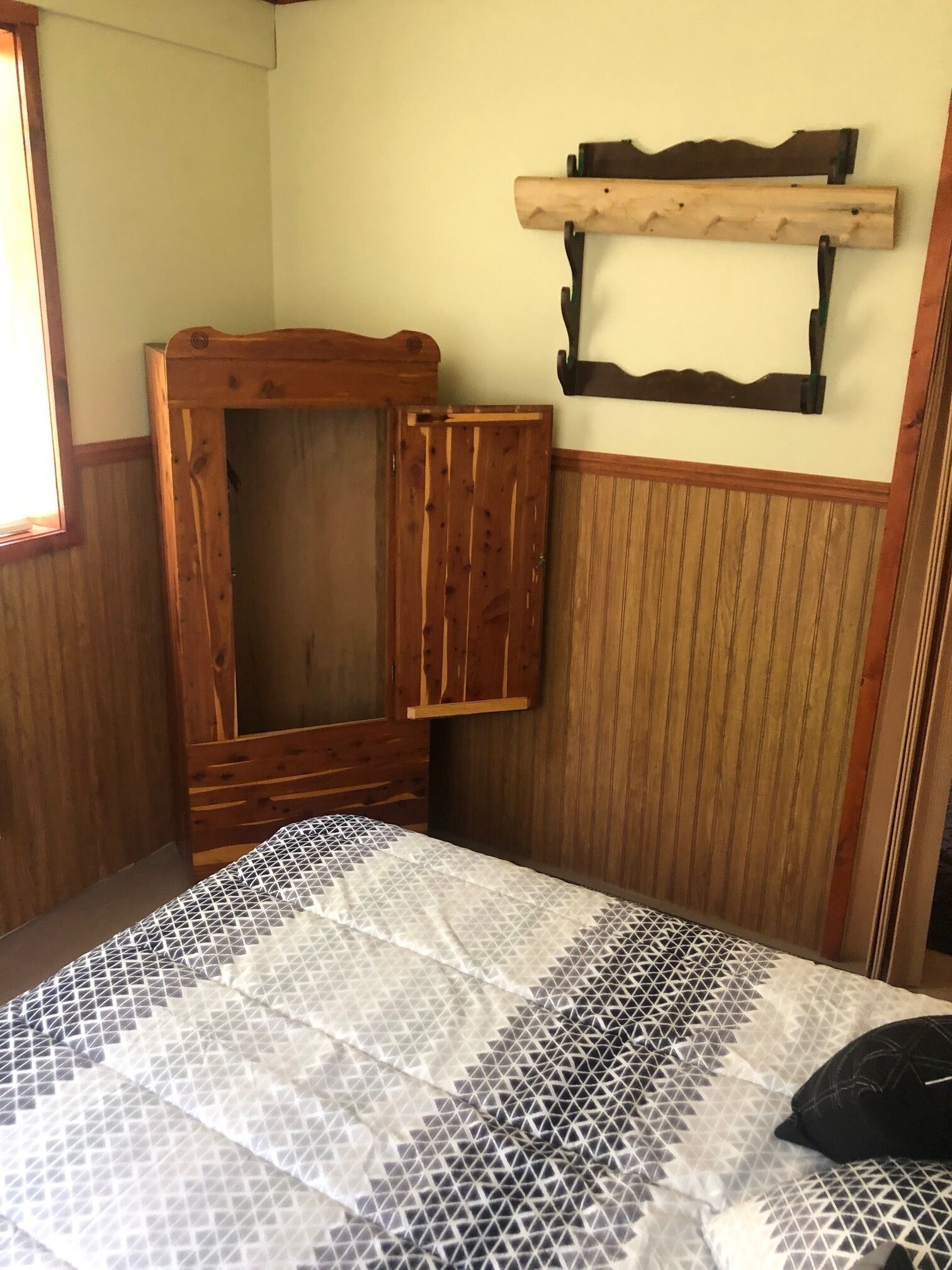 Un dormitorio con cama, armario de madera y estante en la pared.