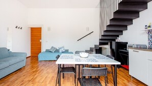 Un espace de vie compact comprenant un coin repas, une kitchenette et un escalier.