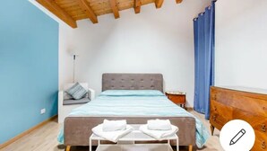 Une chambre à coucher avec un lit, une table de chevet, une commode et une fenêtre avec des rideaux.