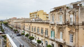 Une rangée de bâtiments historiques dotés de balcons, une rue pavée et des voitures garées.