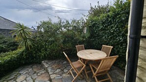 Un patio in pietra con un tavolo rotondo in legno e quattro sedie.