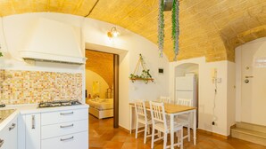A kitchen with white cabinets, a tiled backsplash, and a dining area with a wooden table and chairs.