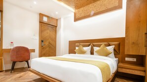 A hotel room with a wooden bed frame, a red chair, and a wooden wardrobe. - Hathili Hotel and Restaurant (Ujjain)