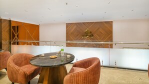 A modern conference room with a round table, cushioned chairs, and a wooden accent wall. - Hathili Hotel and Restaurant (Ujjain)