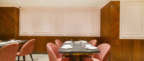 A conference room with a rectangular table, six pink upholstered chairs, and a marble floor.