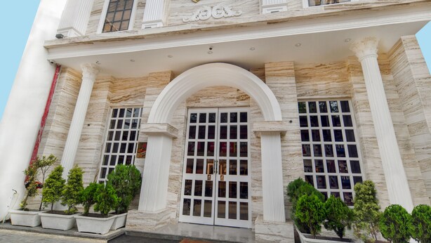 A building with a classical facade, large windows, and a central entrance with a decorative arch. - Hathili Hotel and Restaurant (Ujjain)