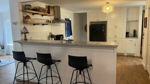 Una cucina moderna con mobili bianchi, un frigorifero nero e un bancone con tre sgabelli.