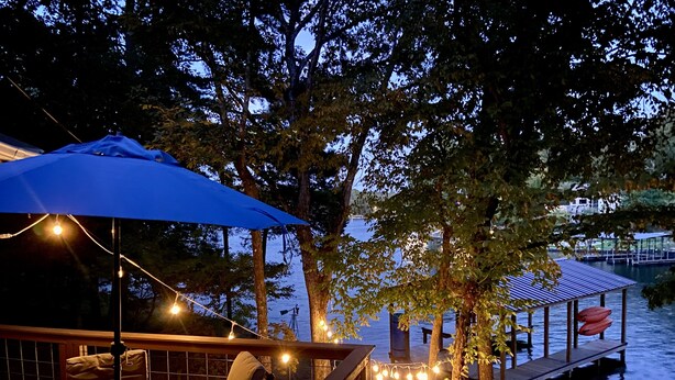 Una terrazza sul lago con posti a sedere all'aperto, luci a tendina e una zona coperta.