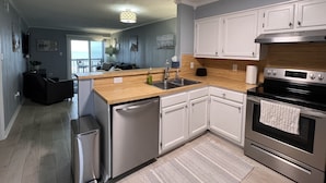 A modern kitchen with white cabinets, stainless steel appliances, and a wooden countertop. - Tequila Sunrise - 2BR Oceanfront (North Myrtle Beach)