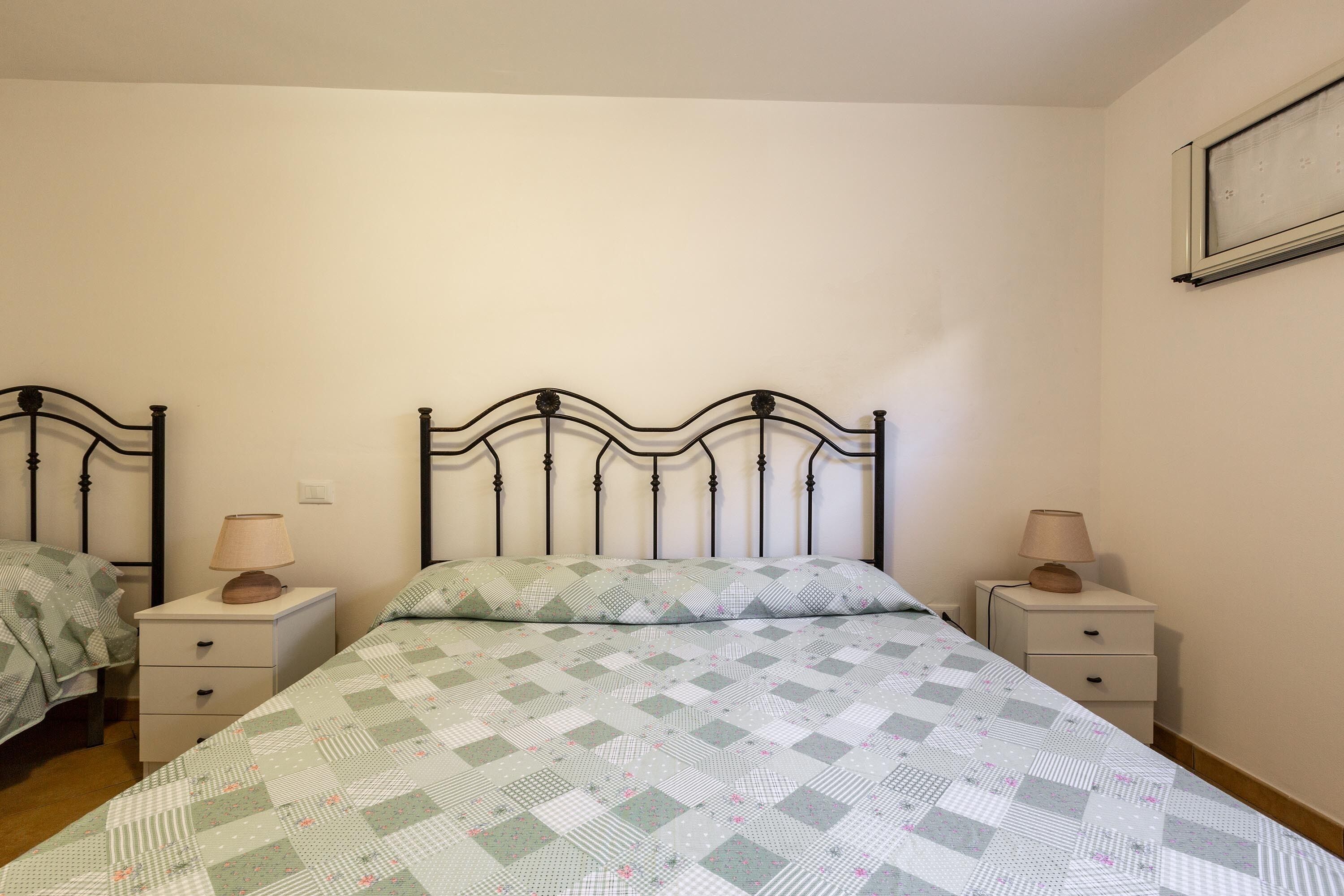 A bedroom with two single beds, each with a nightstand and a lamp. The beds have patterned bedding.