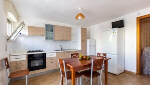 Cocina compacta con comedor, que incluye estufa, horno, refrigerador y una mesa con sillas.