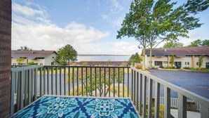 A balcony with a patterned floor, overlooking a parking area and a building with a view of the water. - Lakeside Retreat in Dewittville w/ Pool Access! (Dewittville)