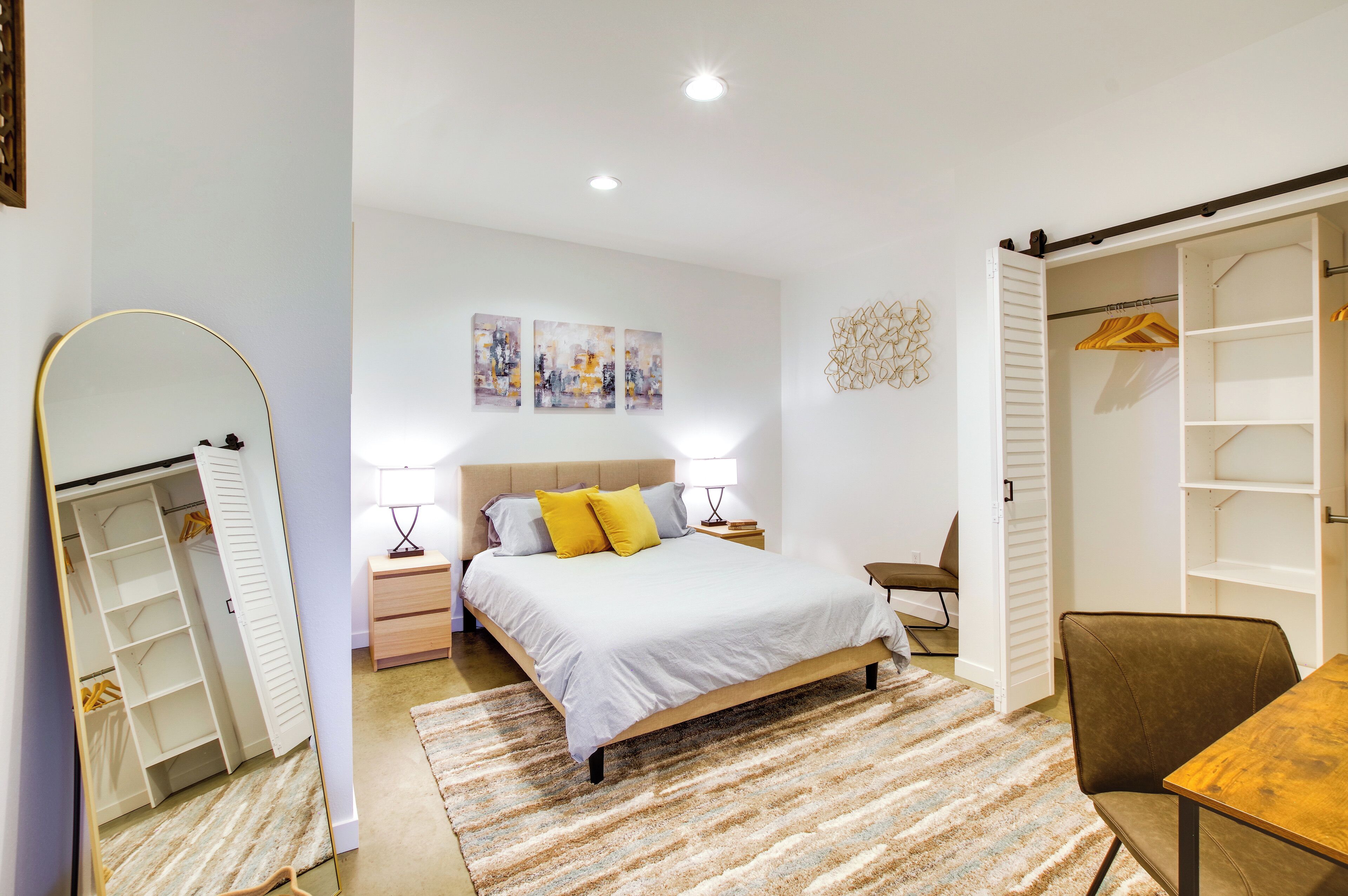A bedroom with a bed, bedside tables, a chair, a desk, and a wardrobe.