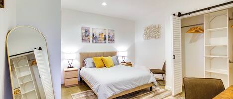 A bedroom with a bed, bedside tables, a chair, a desk, and a wardrobe.