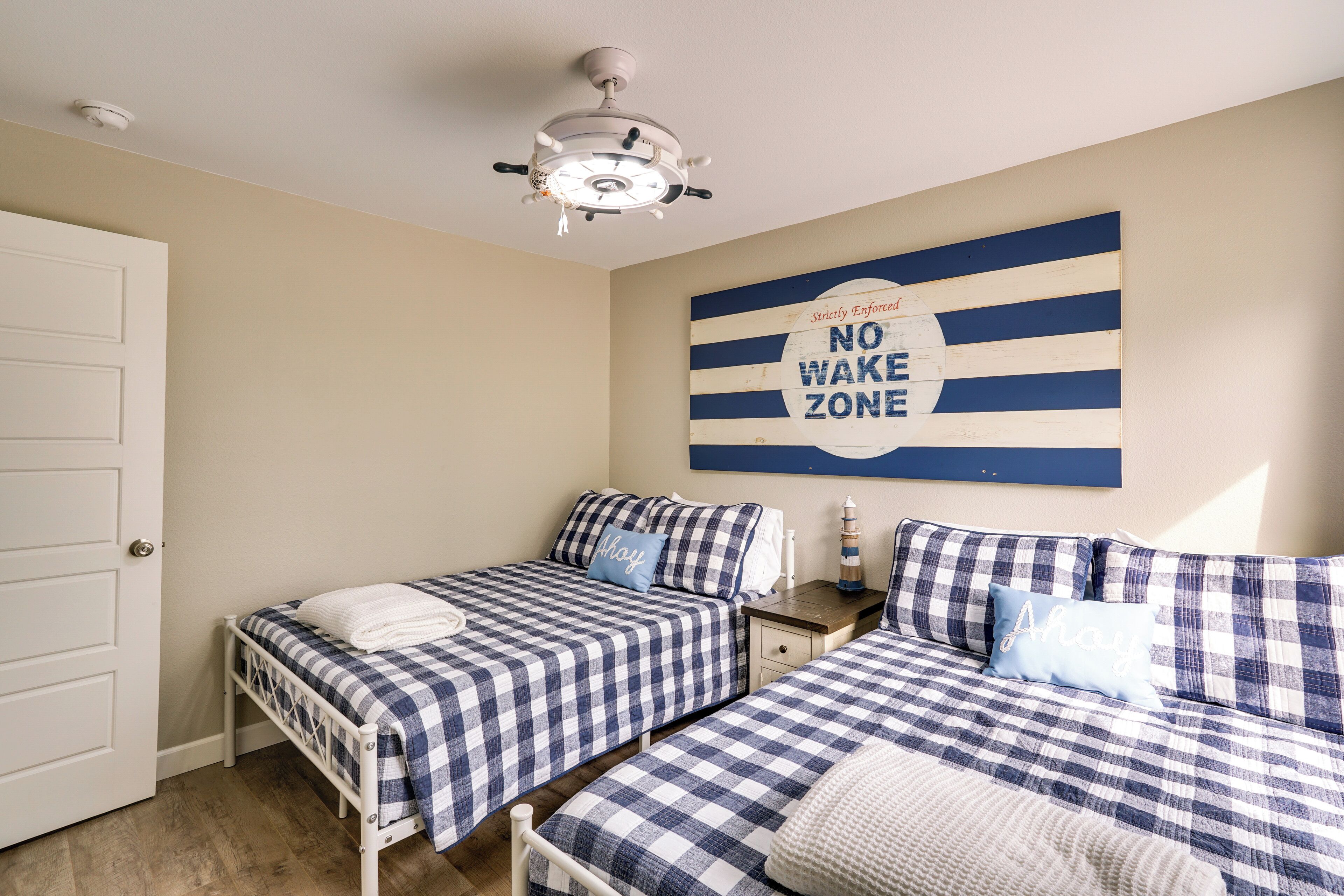Un dormitorio con dos camas, un ventilador de techo, un letrero que dice 'Zona sin despertares' y una puerta.