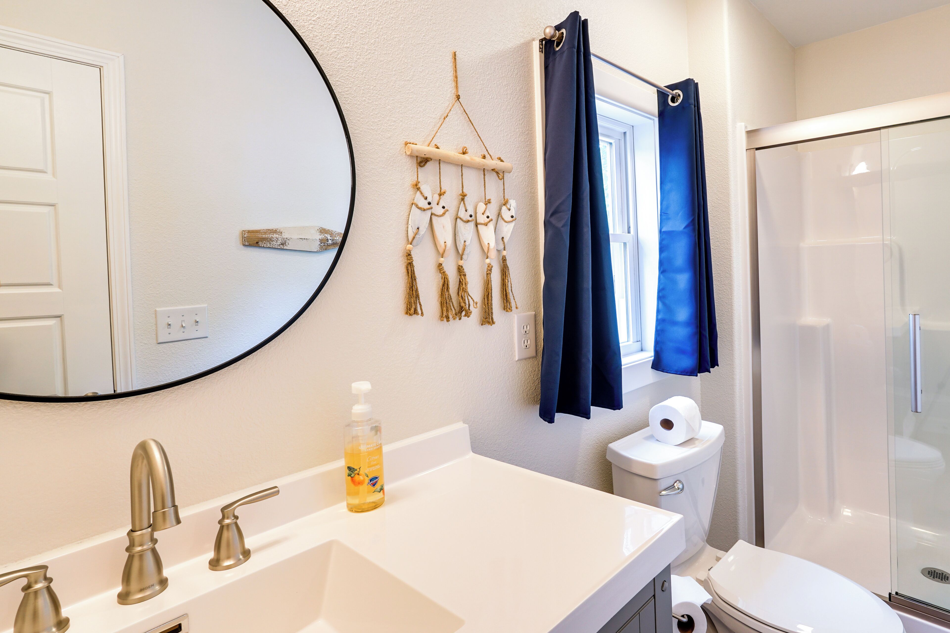 A bathroom with a white sink, a mirror, a toilet, and a glass shower enclosure.