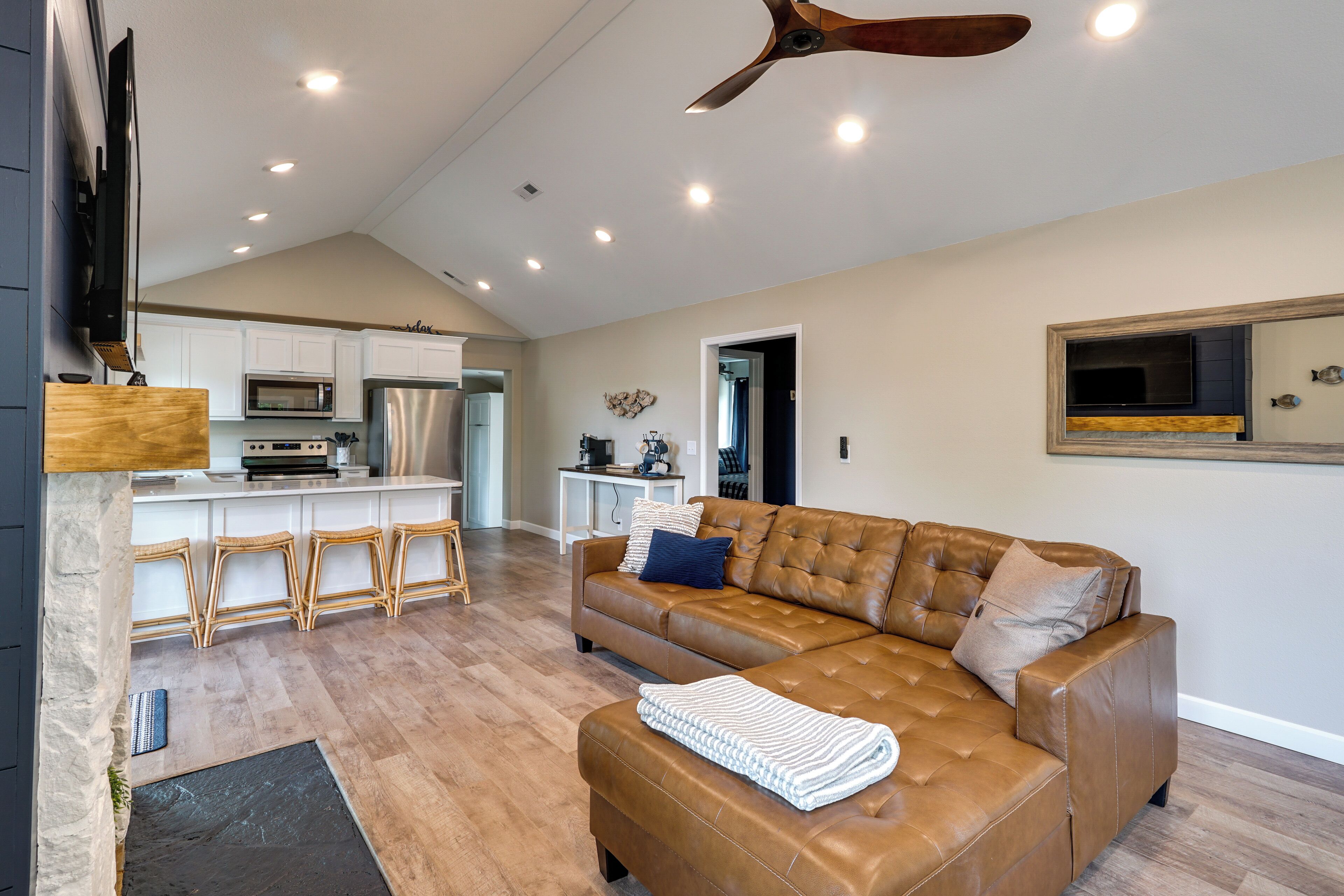 A spacious living area with a brown leather sofa, a wooden coffee table, and a kitchen in the background.
