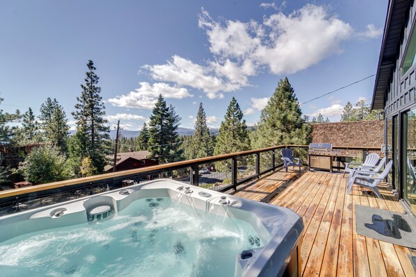 A wooden deck with a hot tub, outdoor seating, and a view of trees and mountains. - Steps to Beach: Family Home w/ Views in Tahoe City (Tahoe City)