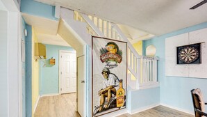 Una stanza con pavimento in legno, una scala, una cornice per freccette e un muro con un affresco.