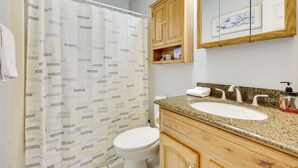 Une salle de bain avec un rideau de douche, des toilettes, un lavabo et des meubles en bois.