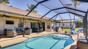 A covered swimming pool area with lounge chairs and a bar area.