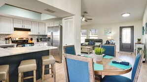 A modern kitchen with white cabinets, stainless steel appliances, and a large island with stools.