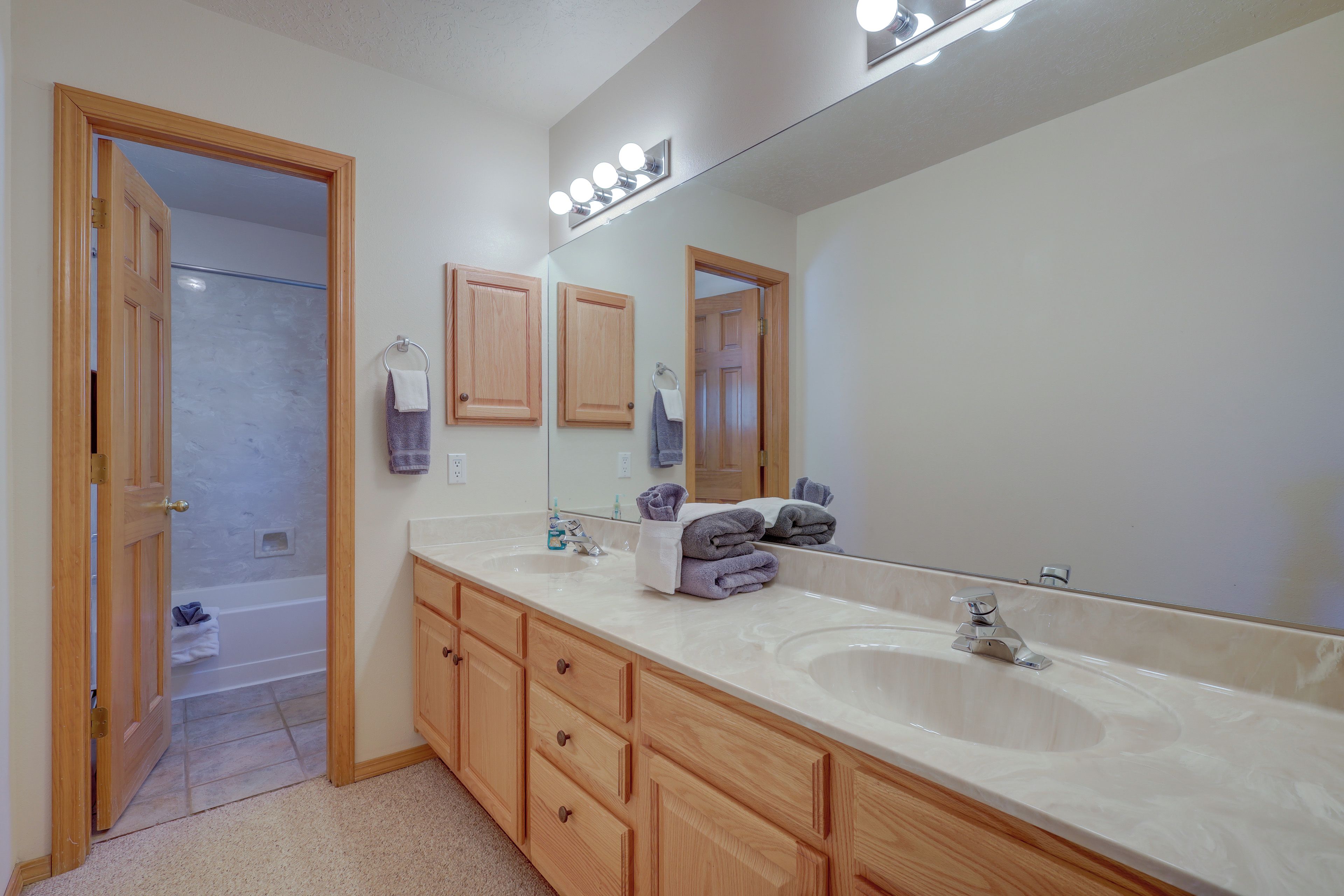 A bathroom with two sinks, wooden cabinets, a large mirror, and a shower area.