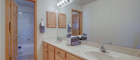 A bathroom with two sinks, wooden cabinets, a large mirror, and a shower area.