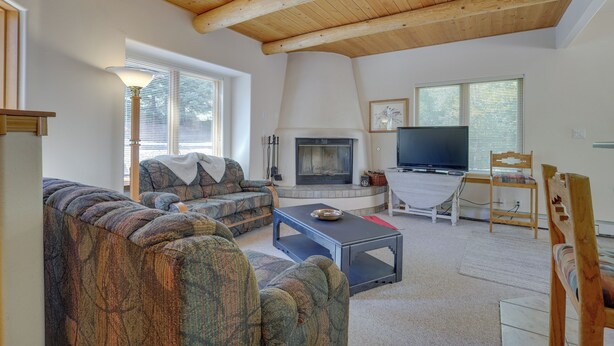 A living room with a fireplace, sofa, television, and wooden ceiling beams. - Secluded Amalia Retreat w/ Cozy Fireplace & Grill! (Amalia)