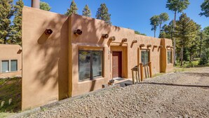 A modern, single-story house with a unique architectural style, featuring a flat roof, large windows, and a chimney. - Secluded Amalia Retreat w/ Cozy Fireplace & Grill! (Amalia)