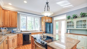 A kitchen with wooden cabinets, a stainless steel stove, and a granite countertop. - Waterfront Lusby Escape w/ Fire Pit & Kayaks! (Lusby)