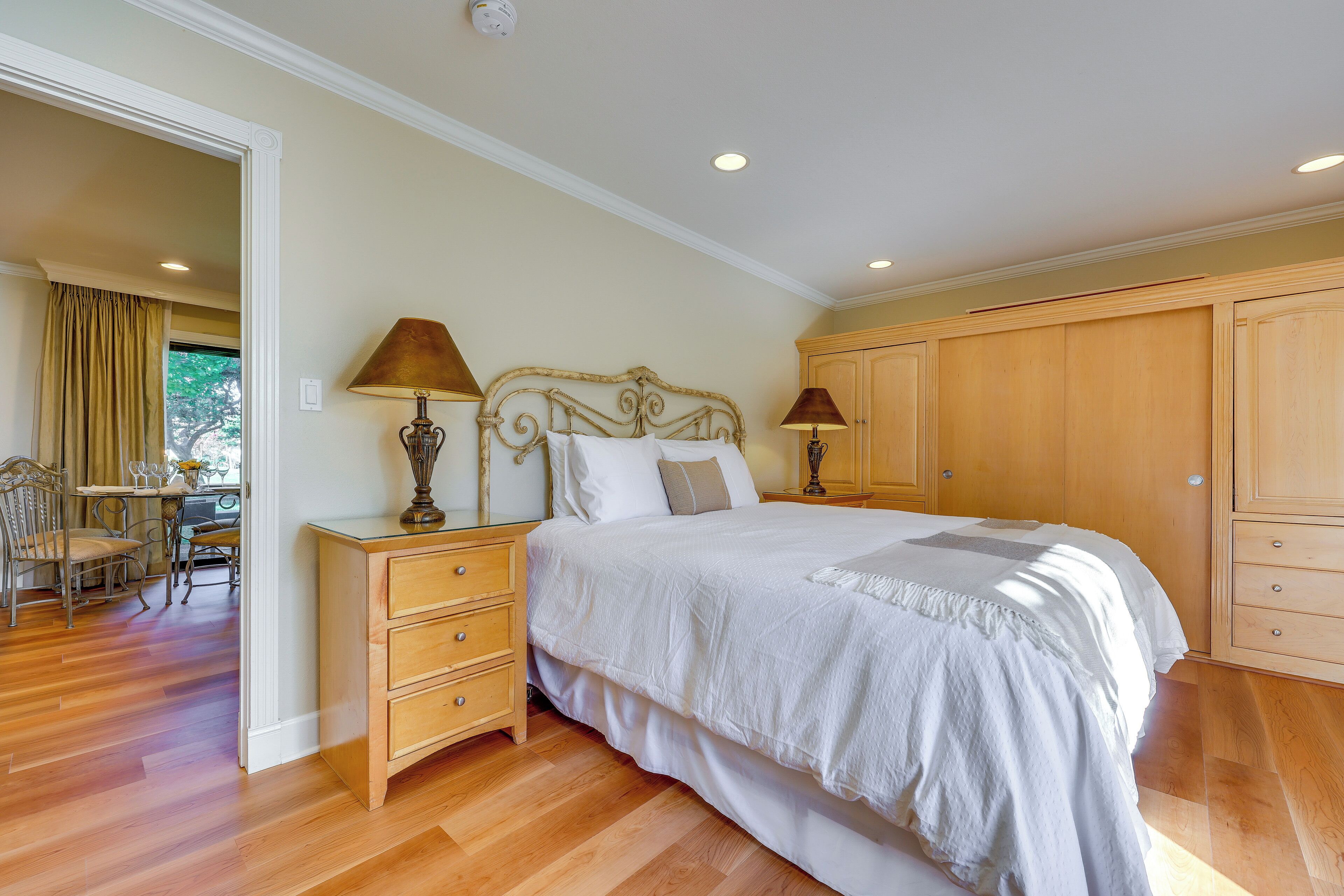 A bedroom with a bed, wooden wardrobe, and a desk with a lamp.