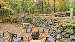 Un espace extérieur aménagé dans un style rustique, avec des murs en pierre, des bancs en bois et des chaises en plastique.