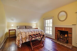 A bedroom with a bed, a fireplace, a window, and a mirror on the wall. - Historic Home in Taylors Falls w/ Patio & Fire Pit (Taylors Falls)