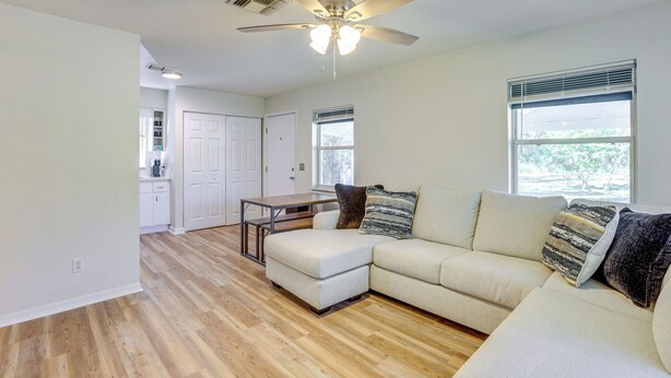 A modern living room with a sectional sofa, a ceiling fan, and a dining area with a table and chairs. - Williston Home w/ Yard: 6 Mi to Devils Den Spring (Williston)