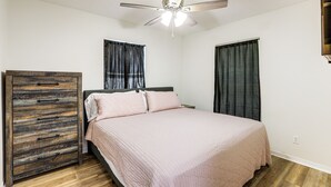A bedroom with a bed, a ceiling fan, and a wooden dresser. - Williston Home w/ Yard: 6 Mi to Devils Den Spring (Williston)