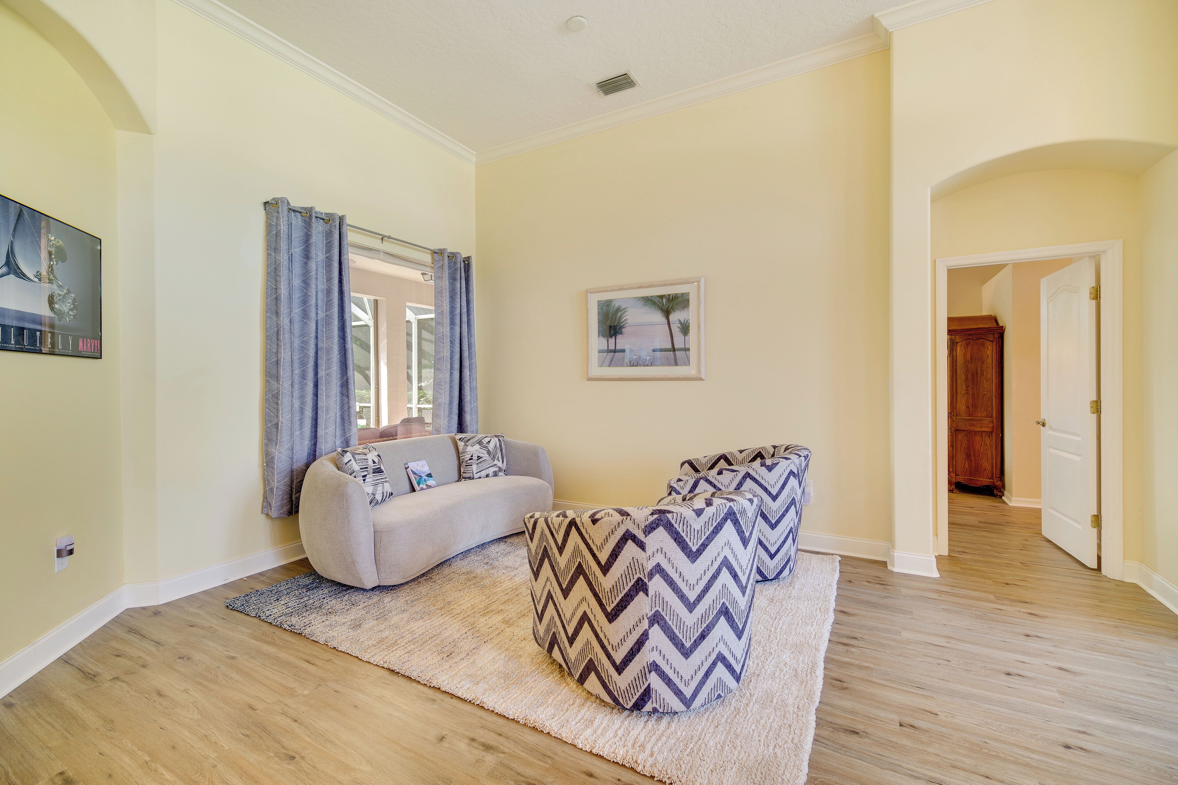 A living room with a sofa, patterned ottomans, a rug, and a painting on the wall.