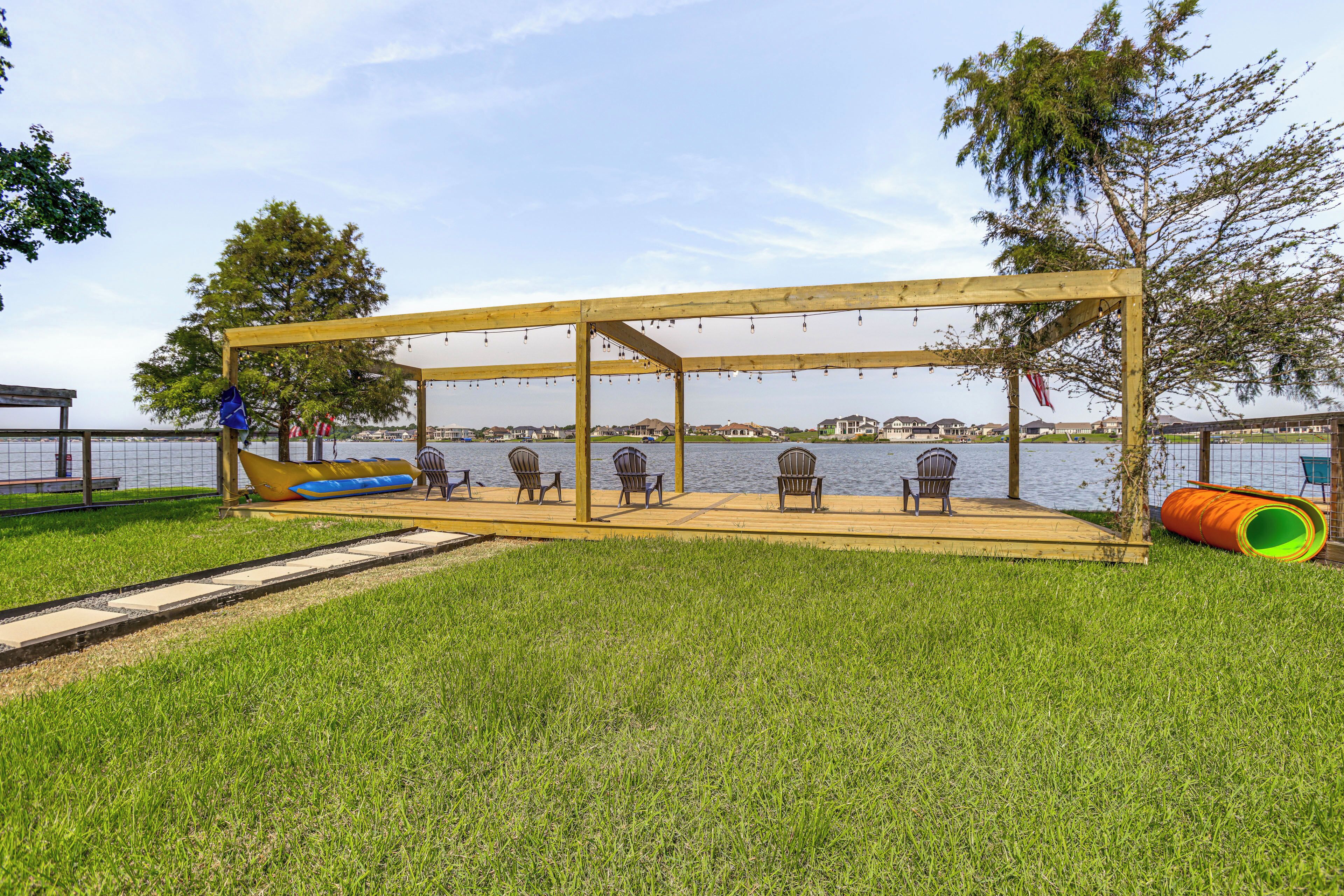 A wooden deck with chairs and a swing set overlooking a body of water.